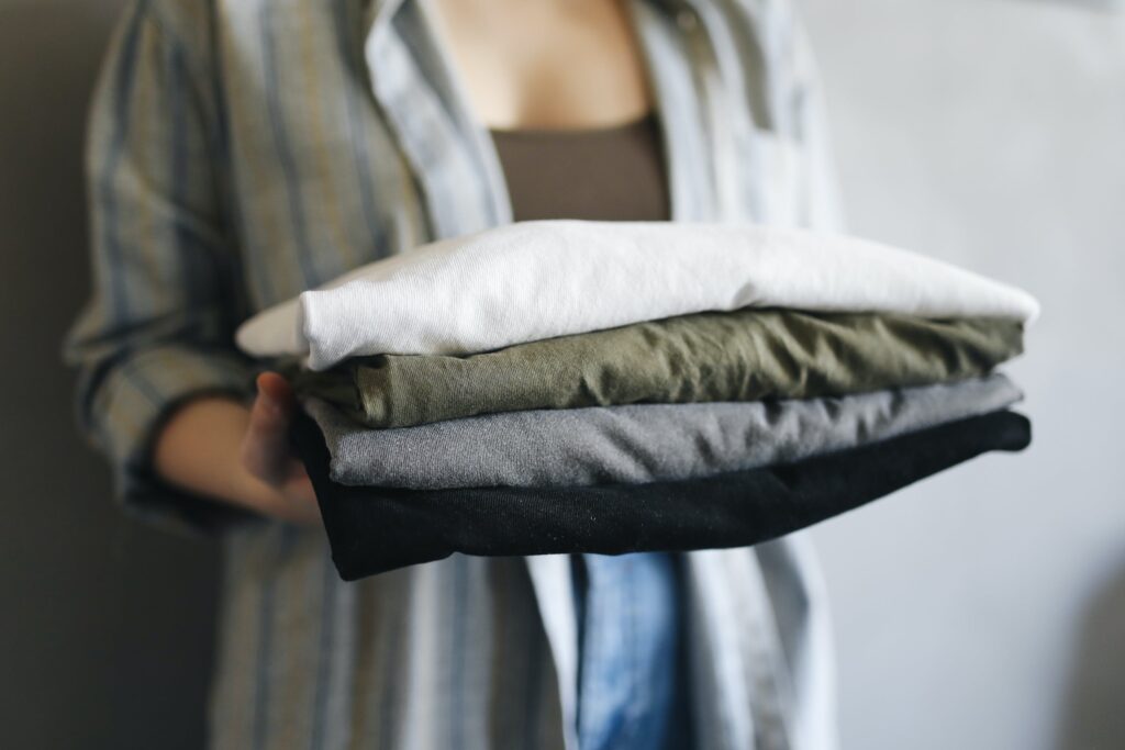 A Person Holding a Stack of Neatly Folded Shirts